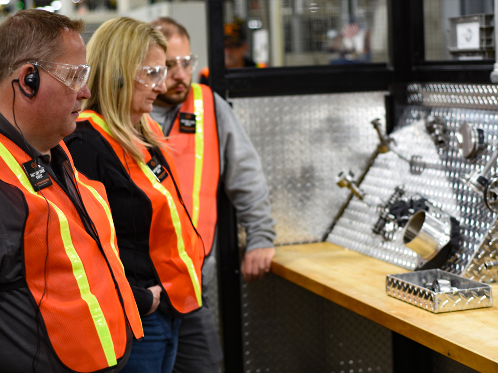 Workers in safety vests observing factory equipment