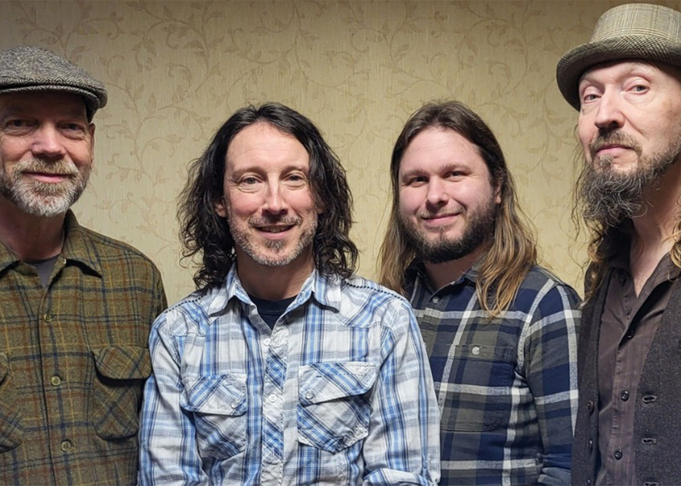 Four people standing together against a patterned wall background