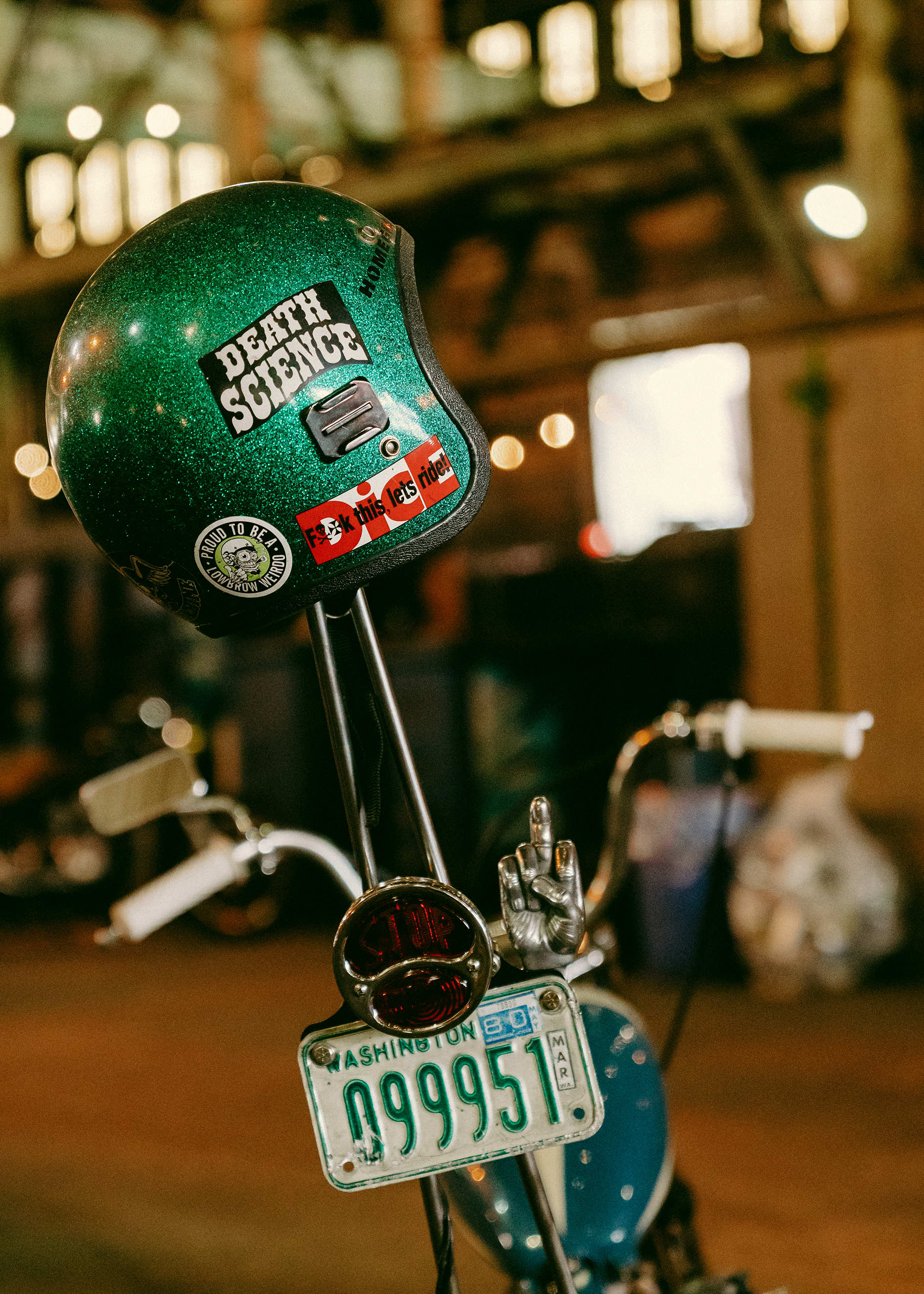A sparkling green helmet covered in riding stickers sits on the back of a blue chopper.
