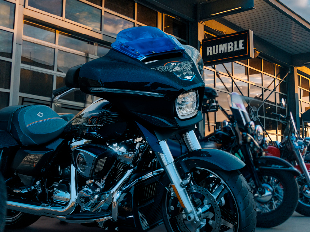 Motorcycle parked outside building with “Rumble” sign