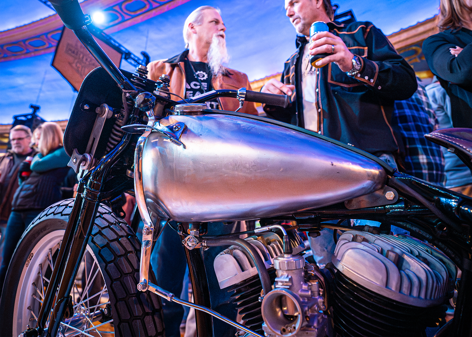 Details of a polished bare metal tank with a hand shifter on a vintage flathead motorcycle 
