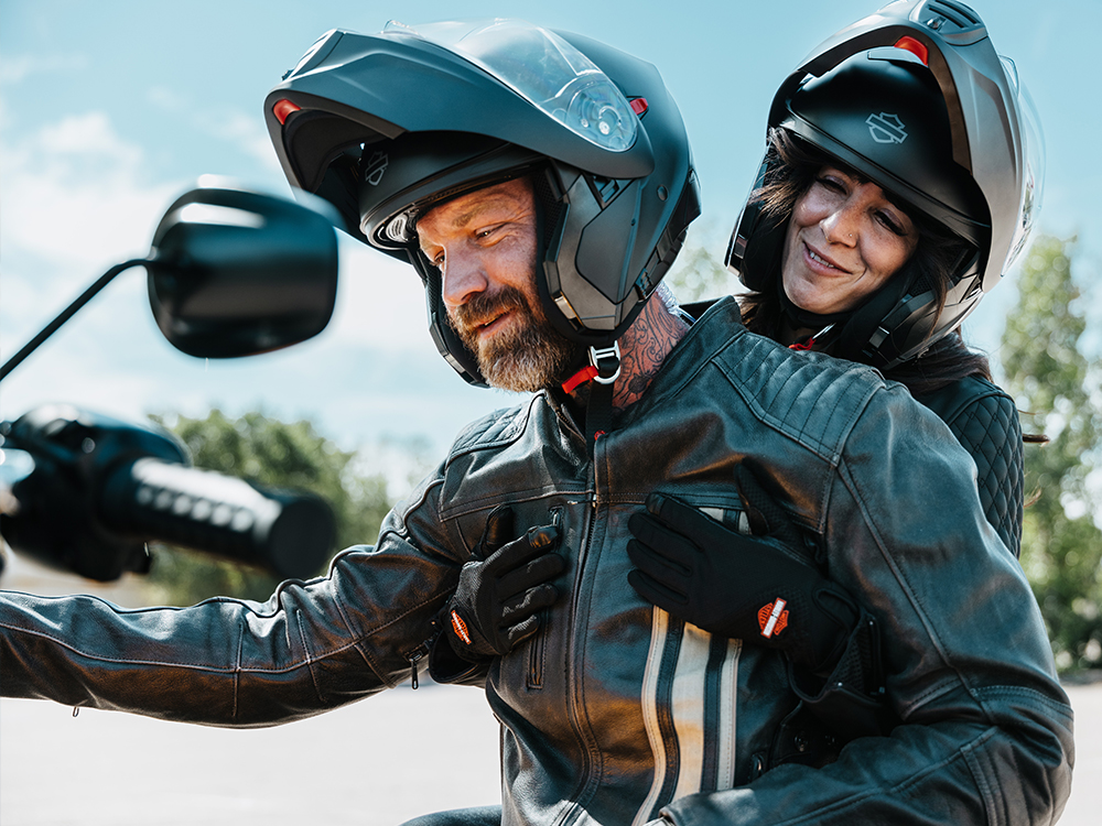 Two riders wearing helmets on a motorcycle