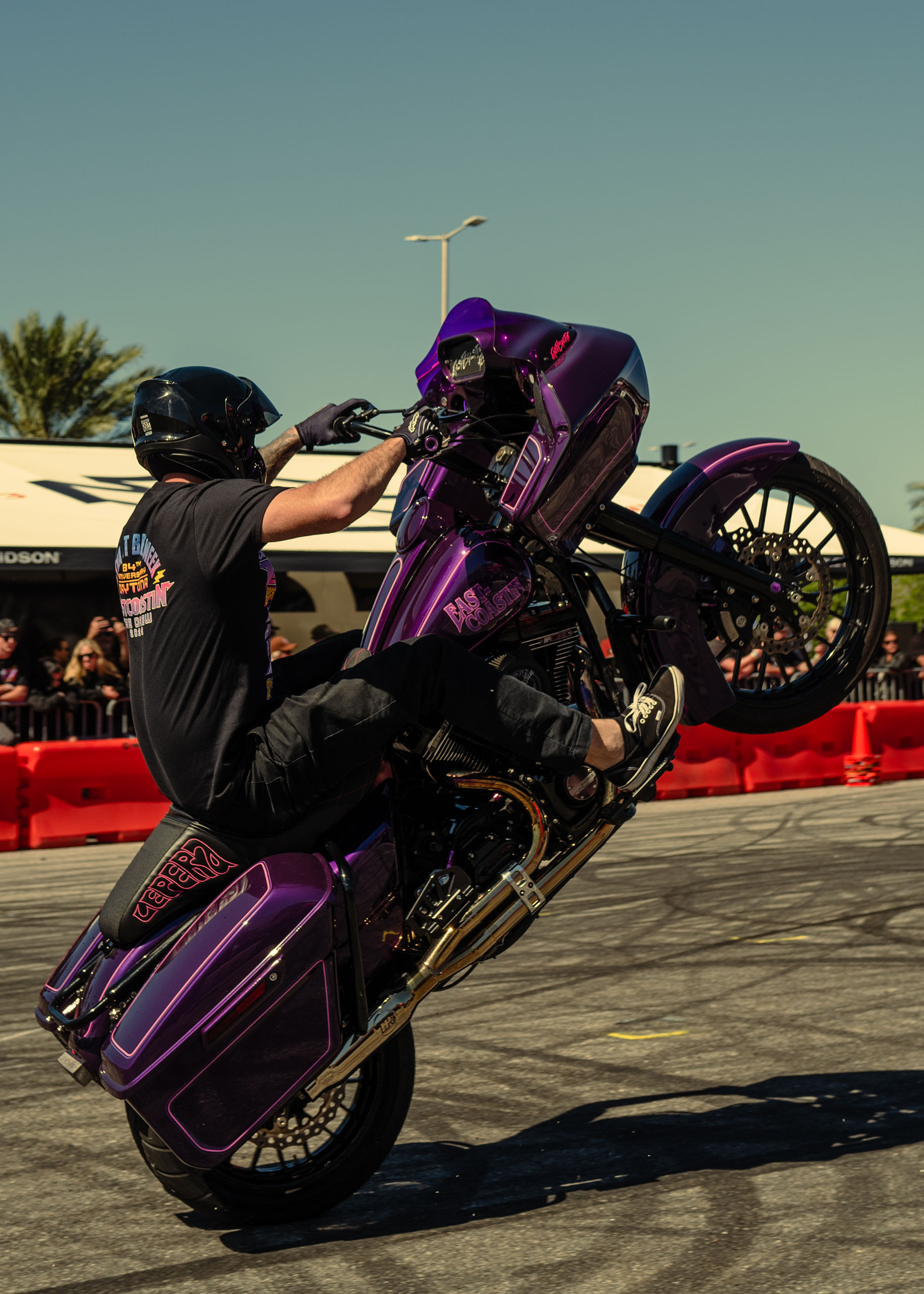 A person wheelies a purple road glide in a stunt show