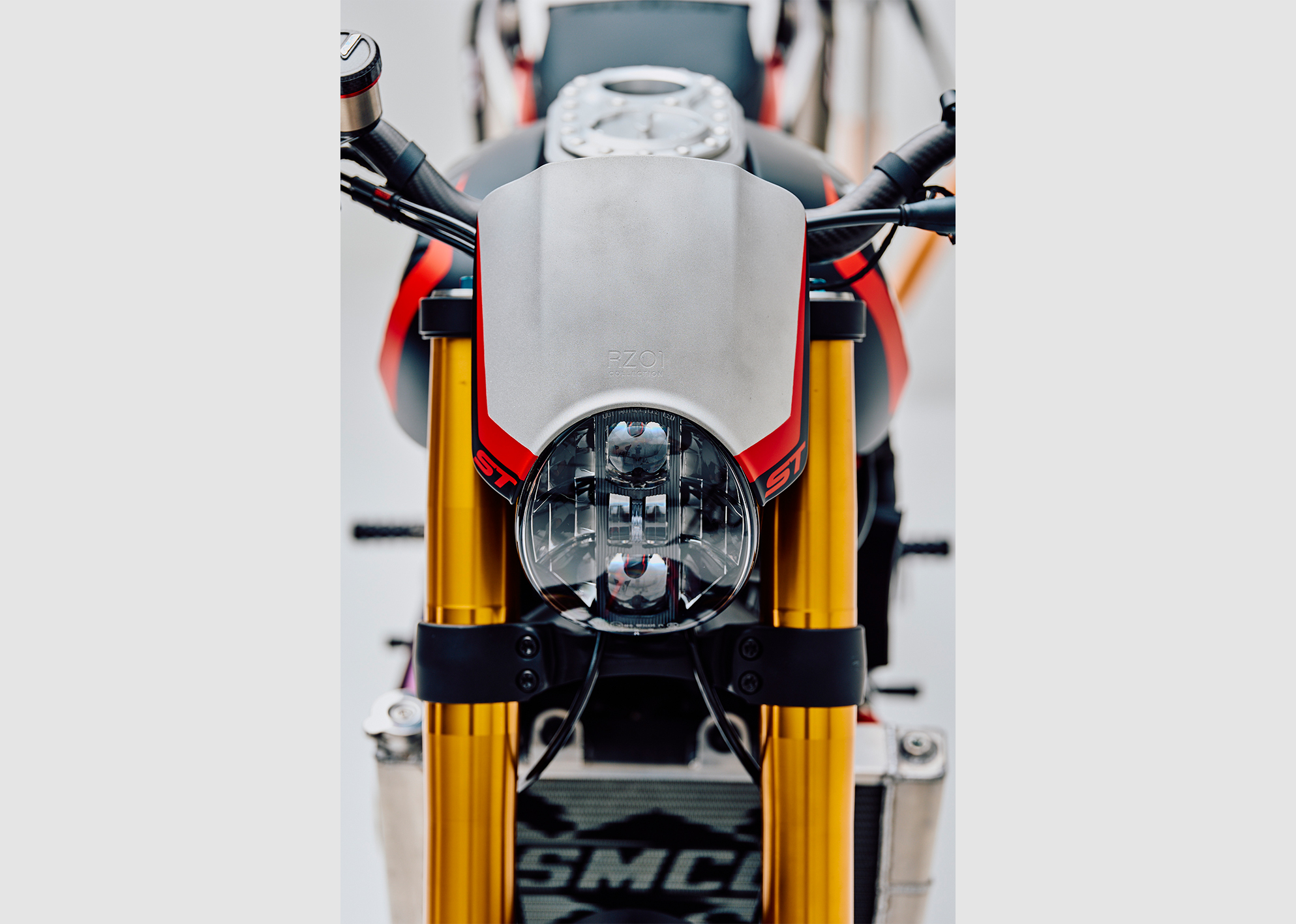 Front view of the custom Pan America ST’s round LED headlight, gold forks, and engraved fuel tank cap.