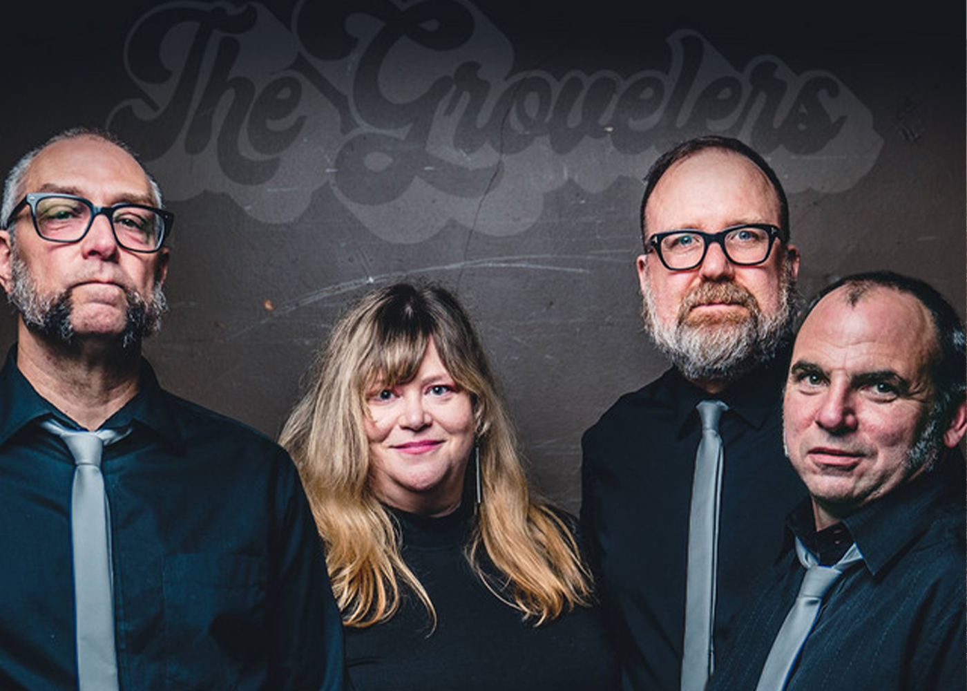 Four band members posing together in front of “The Grownlers” sign