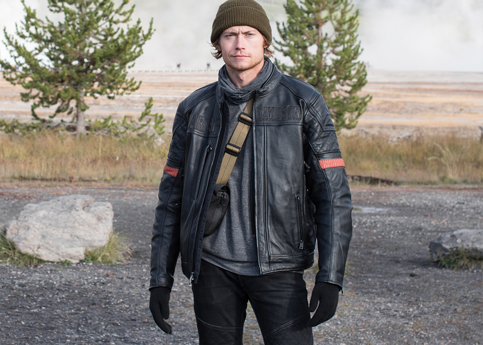 A man in a leather jacket smirks at the camera 