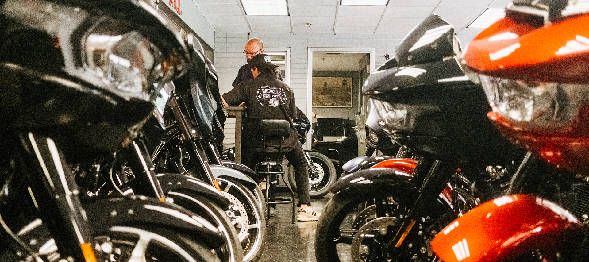 Staff members of Boswell’s Harley-Davidson are seen conversing beyond rows of bikes in the foreground.