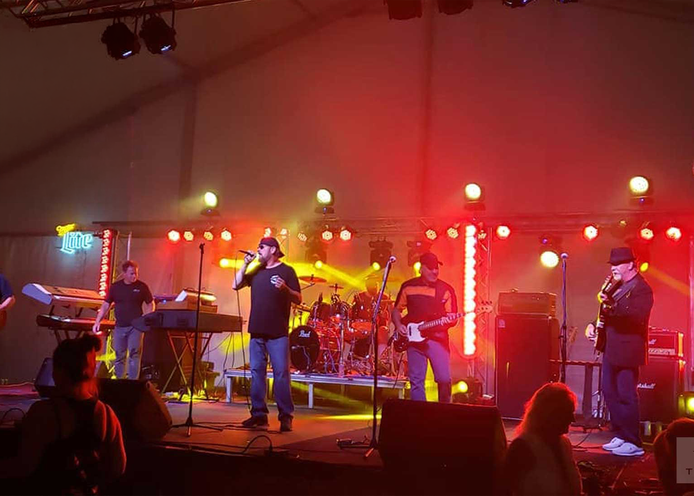 Band performing on stage under colorful lights in indoor concert setting
