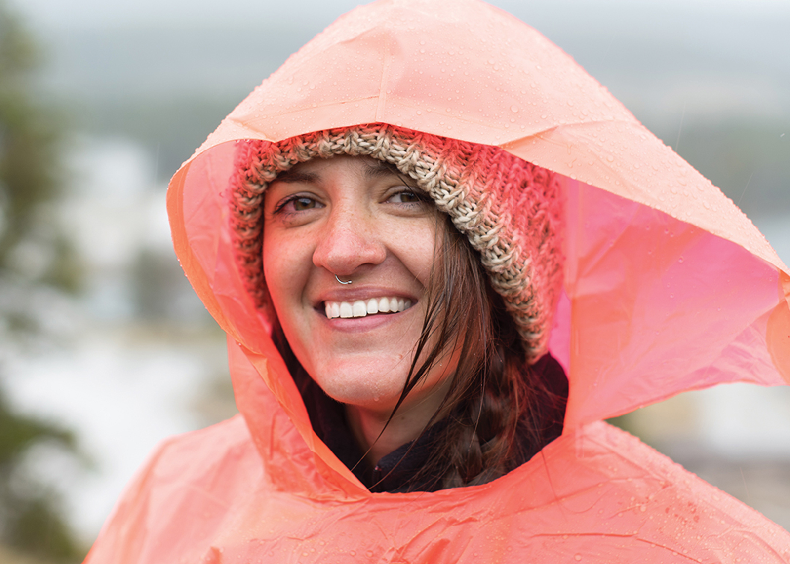 A woman with a nose ring smiles in a poncho 