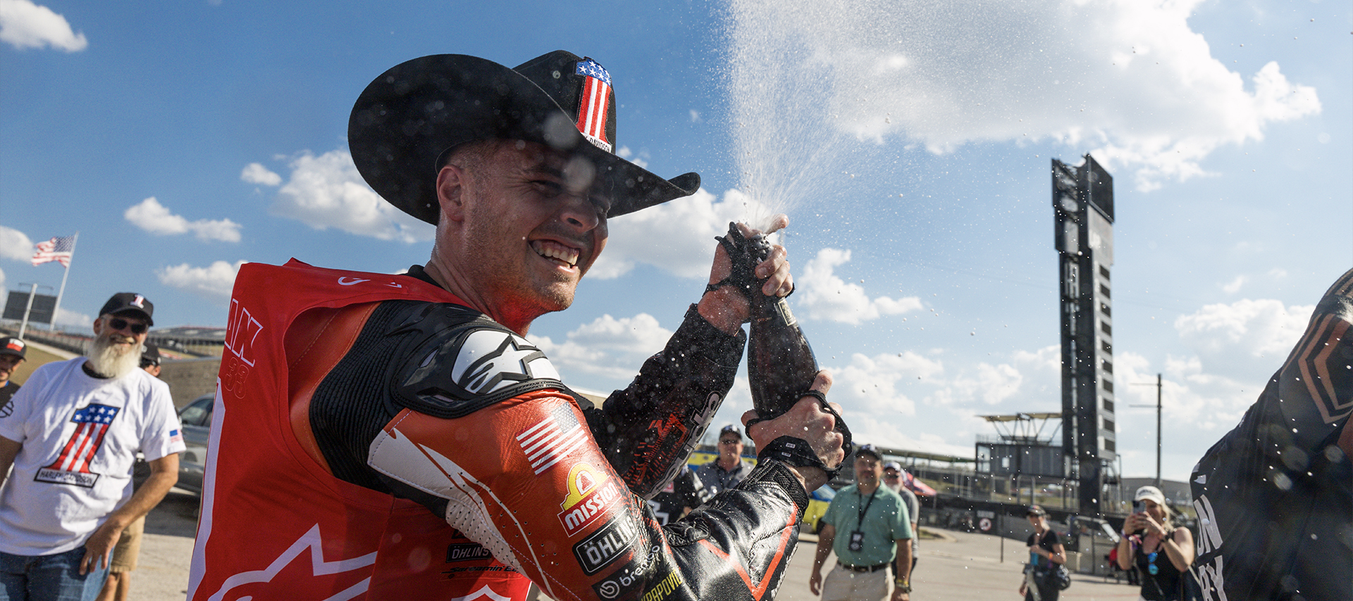 Kyle Wyman wearing a cowboy hat sprays champagne into the air after winning the 2025 King Of The Baggers championship.