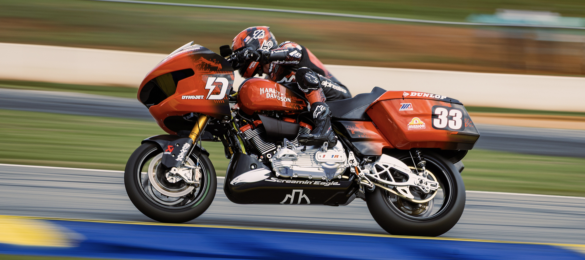 A closeup of Bradley Smith riding his bright orange bagger around a curve on the track.  