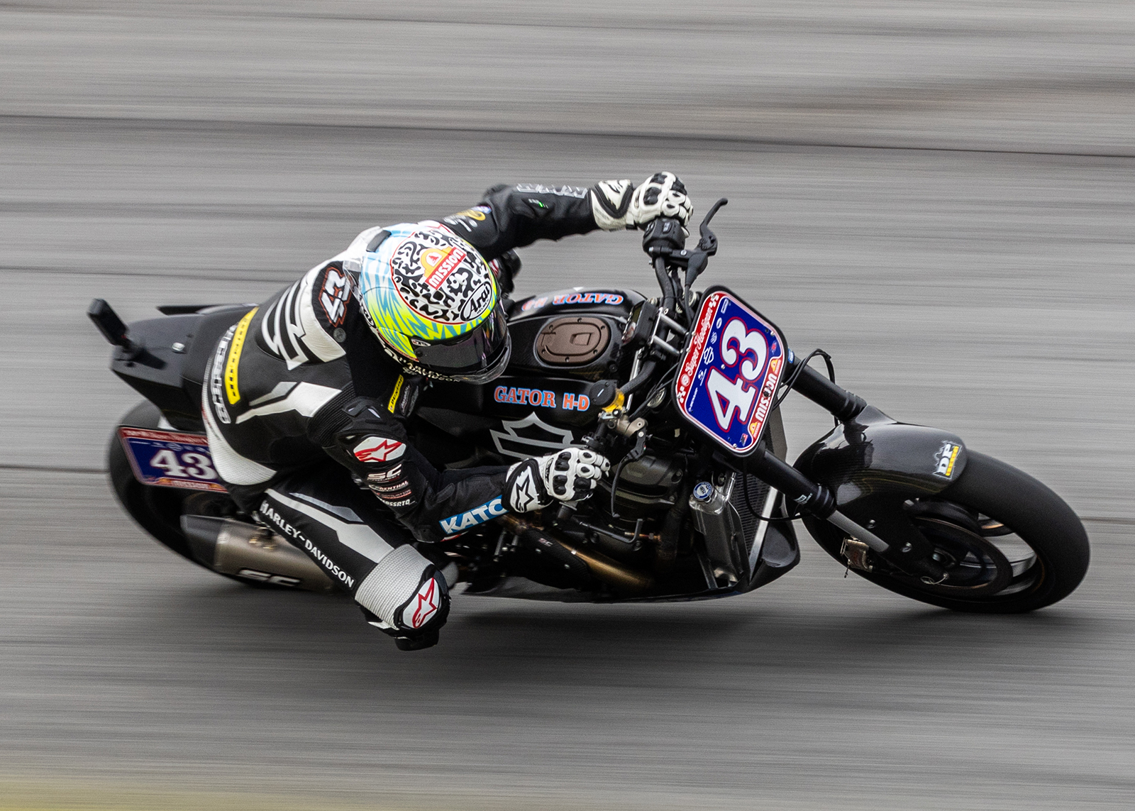 A racer on his black Hooligan speeds around a curve, knee just above the ground.