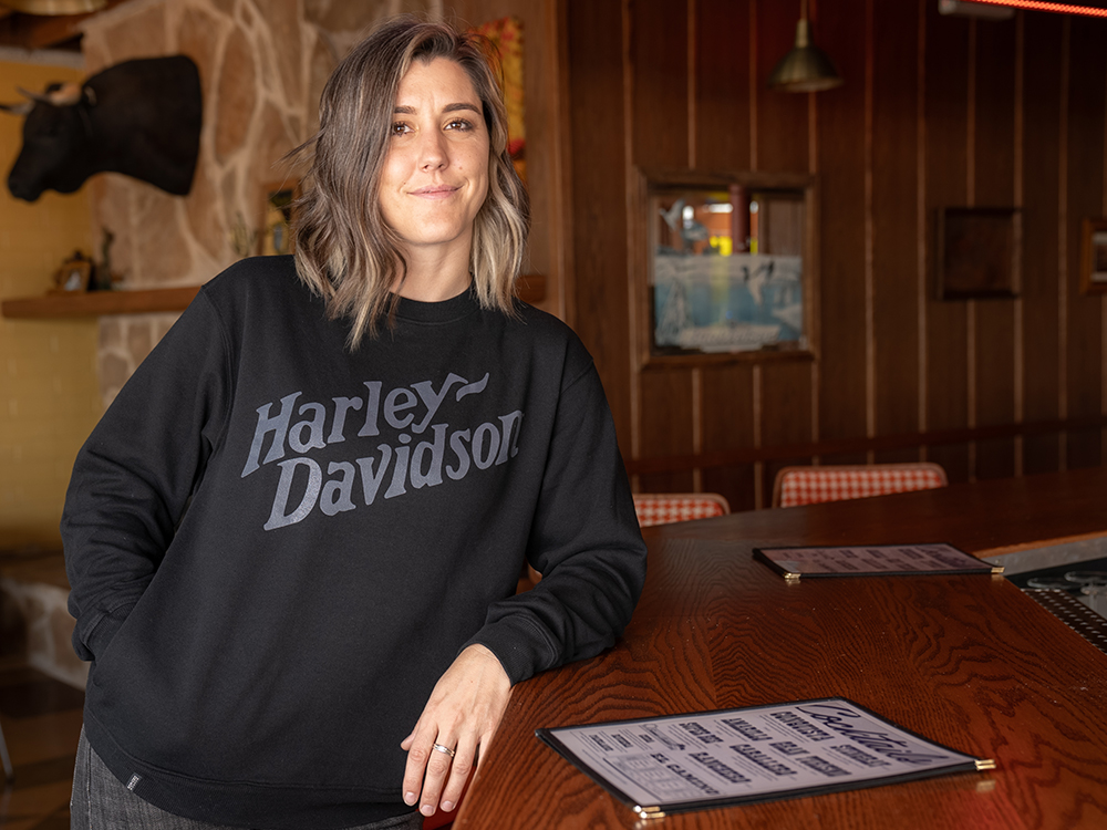 woman wearing black long-sleeve tshirt leaning on a bar
