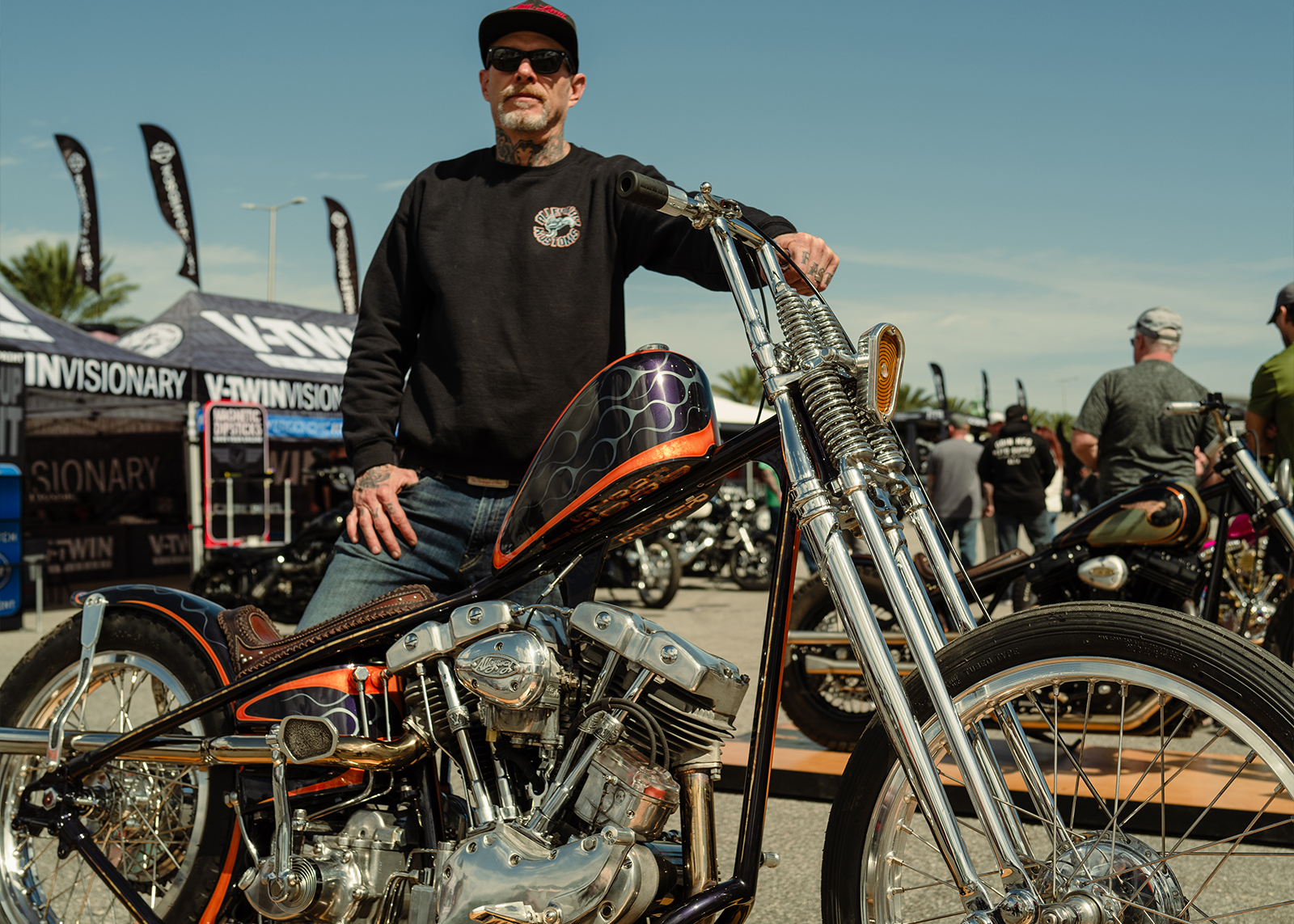 A man in a black sweatshirt poses with his chopper 