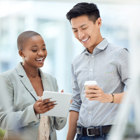 Black woman with iPad in hand and asian man smiling with coffee in hand