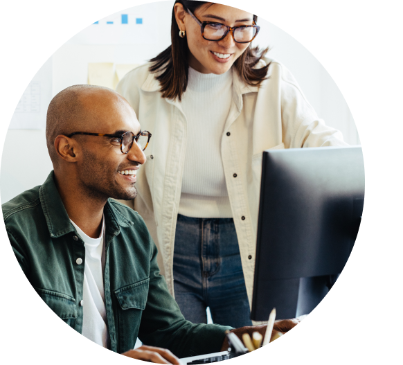 Man sitting and woman standing in front of computer smiling