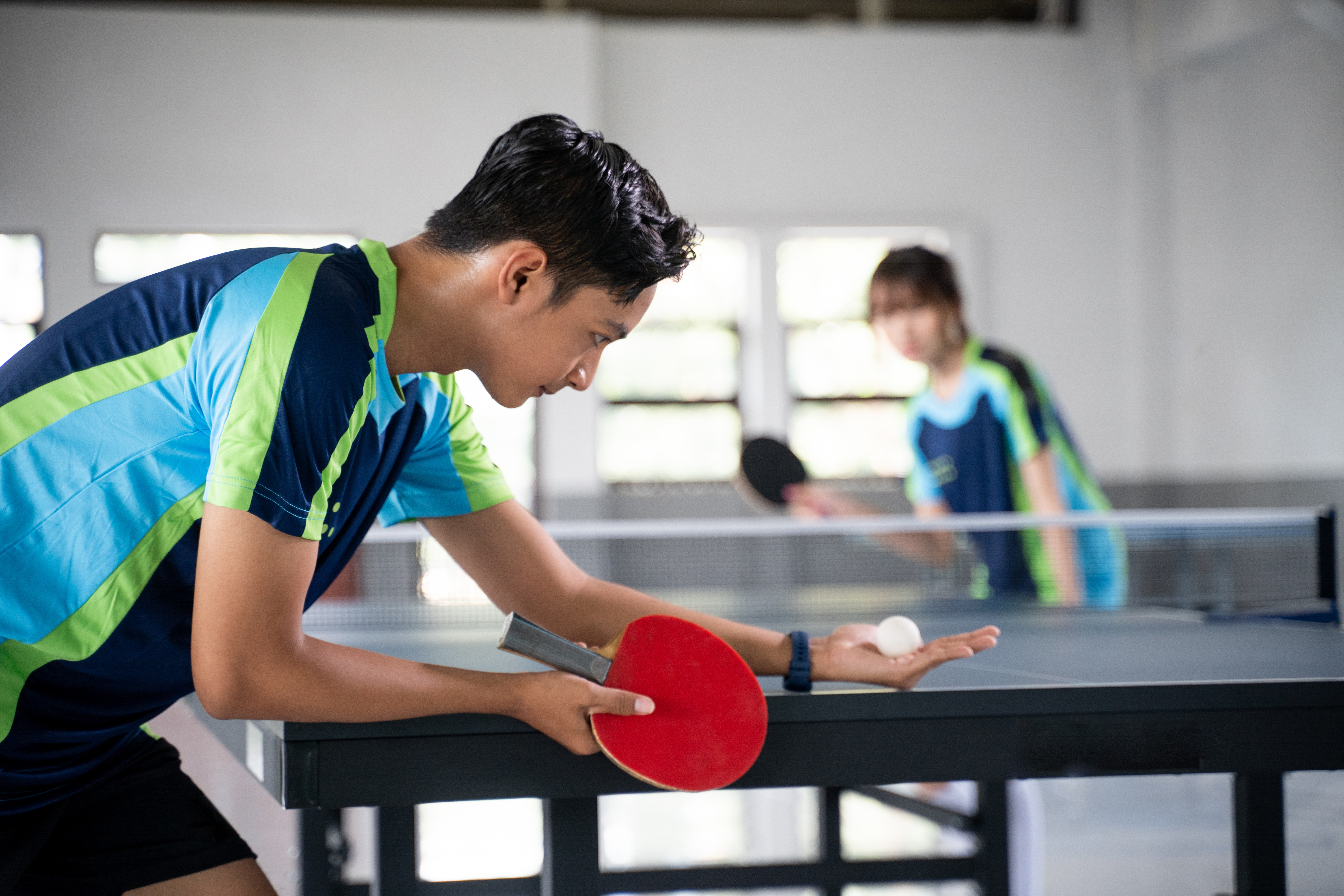 Photo de deux personnes qui jouent au tennis de table.