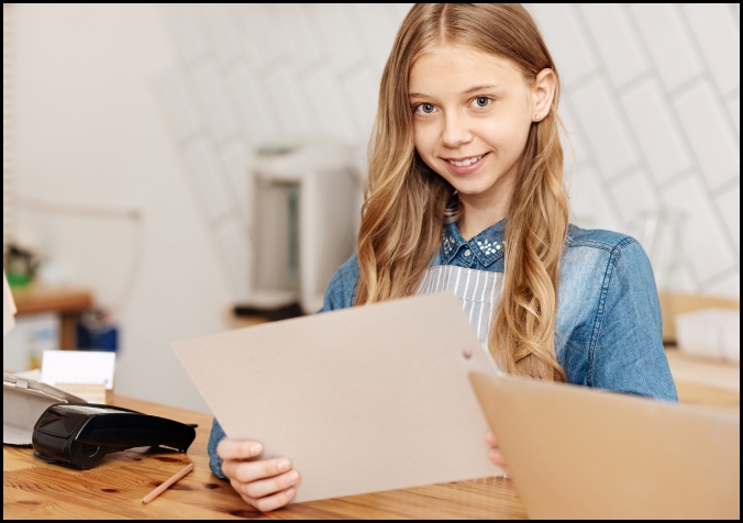 Photo d’une jeune fille qui tient une feuille de papier.  