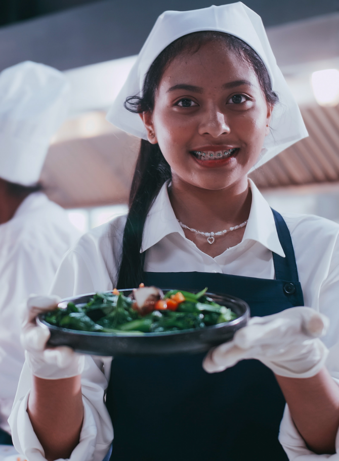 Photo d’une jeune cheffe cuisinière. Elle tient un plat.