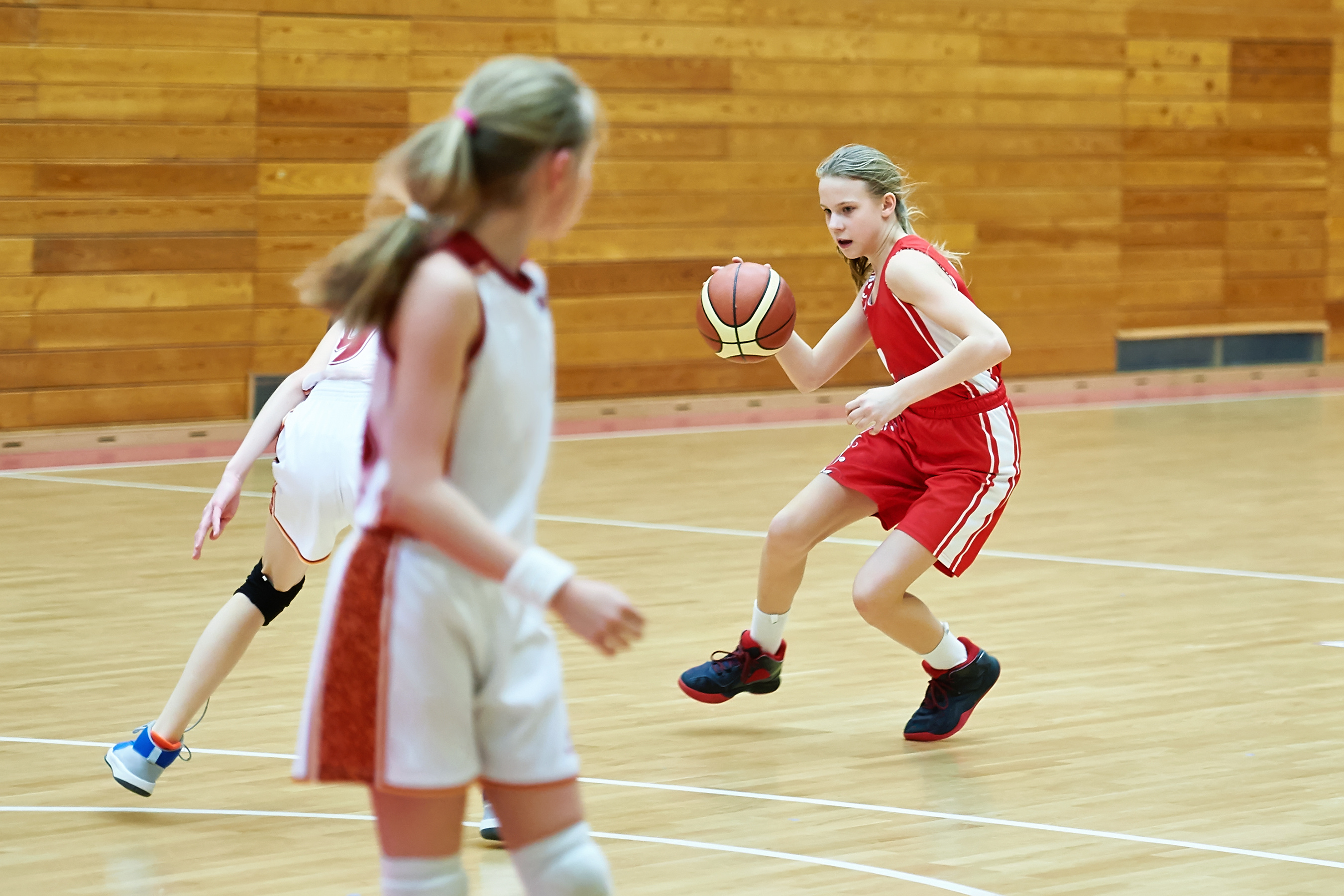 Photo de trois jeunes filles jouant au basket.