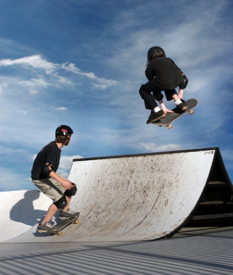 Photo de deux jeunes pratiquant la planche à roulettes dans un planchodrome. 