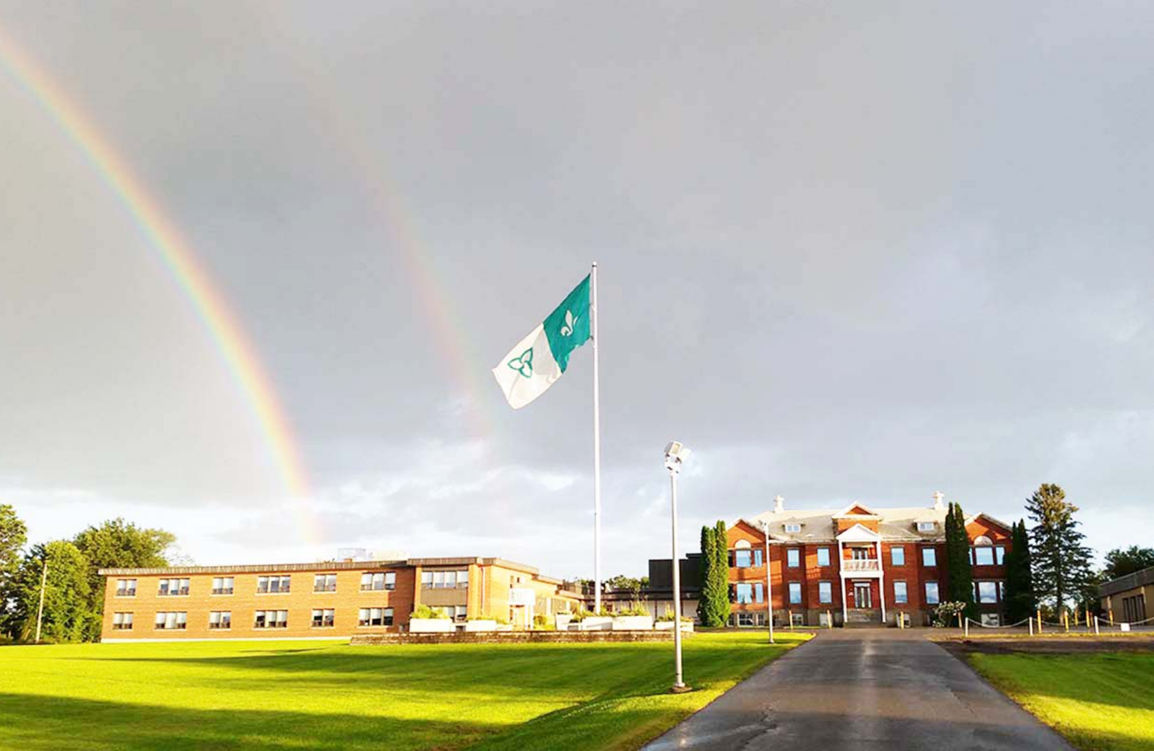 Photo d’un drapeau franco-ontarien devant un arc-en-ciel.