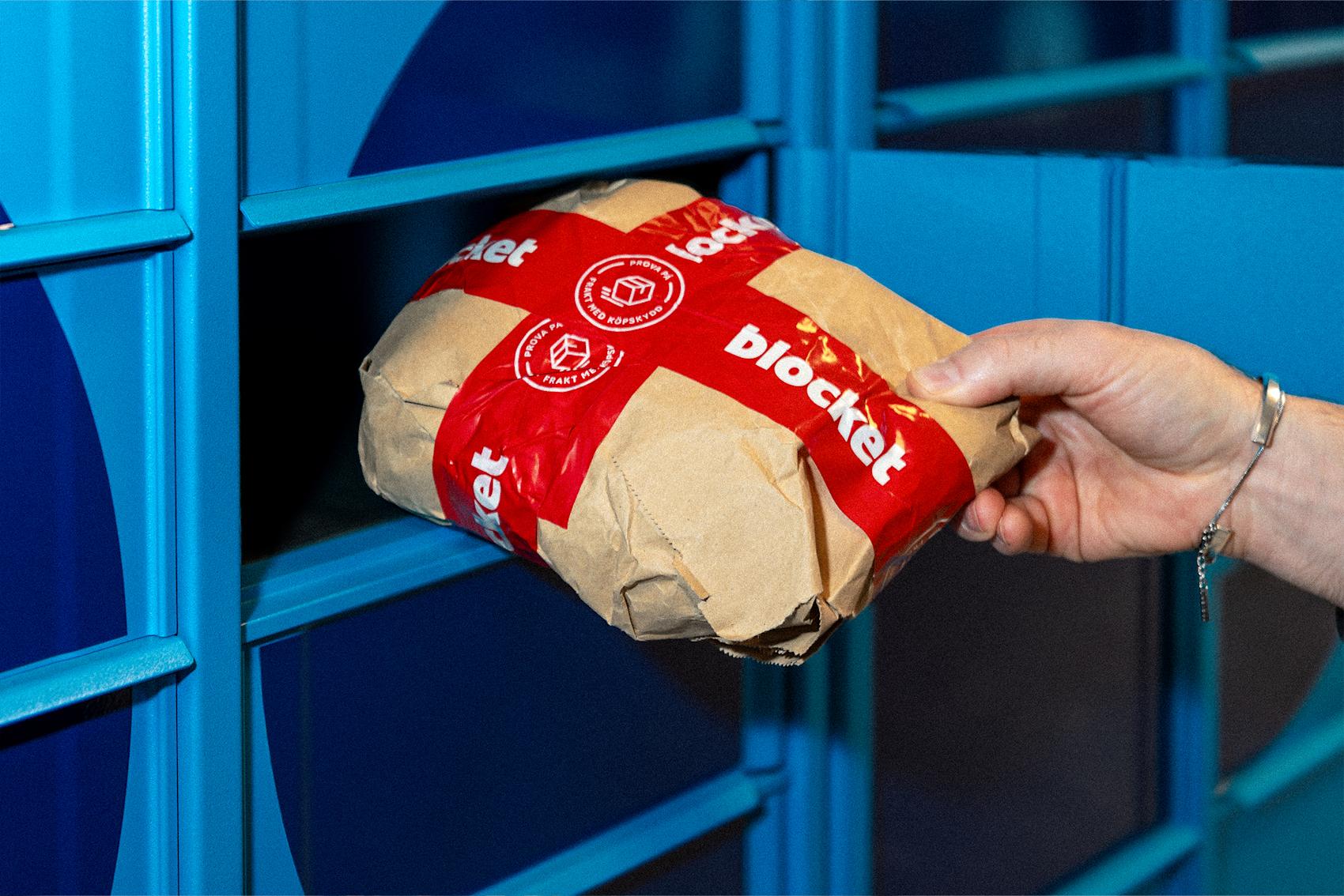 Paket med röd blocket-tejp hämtas från blå paketbox