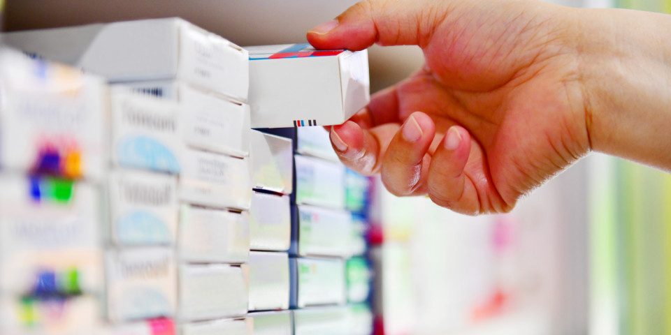 Pharmacist taking pill packets out in pharmacy