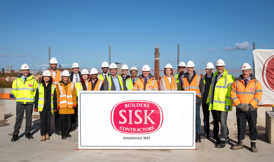 pictures of sector leaders in construction wear in front of sisk sign on bhic building site