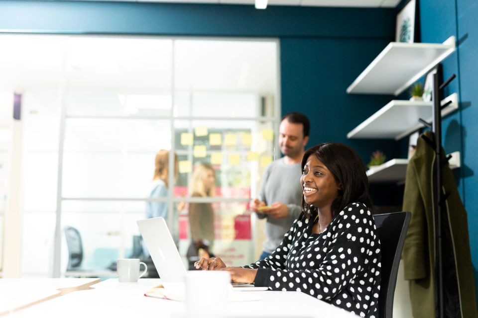 woman on laptop and man standing in office 