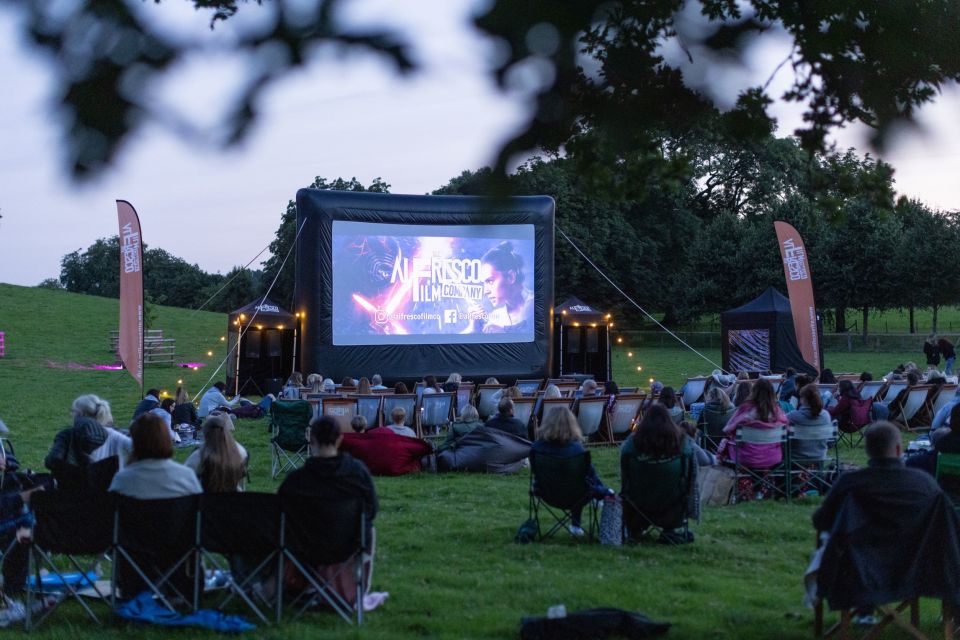 cinema screen in field with group of people watching a film