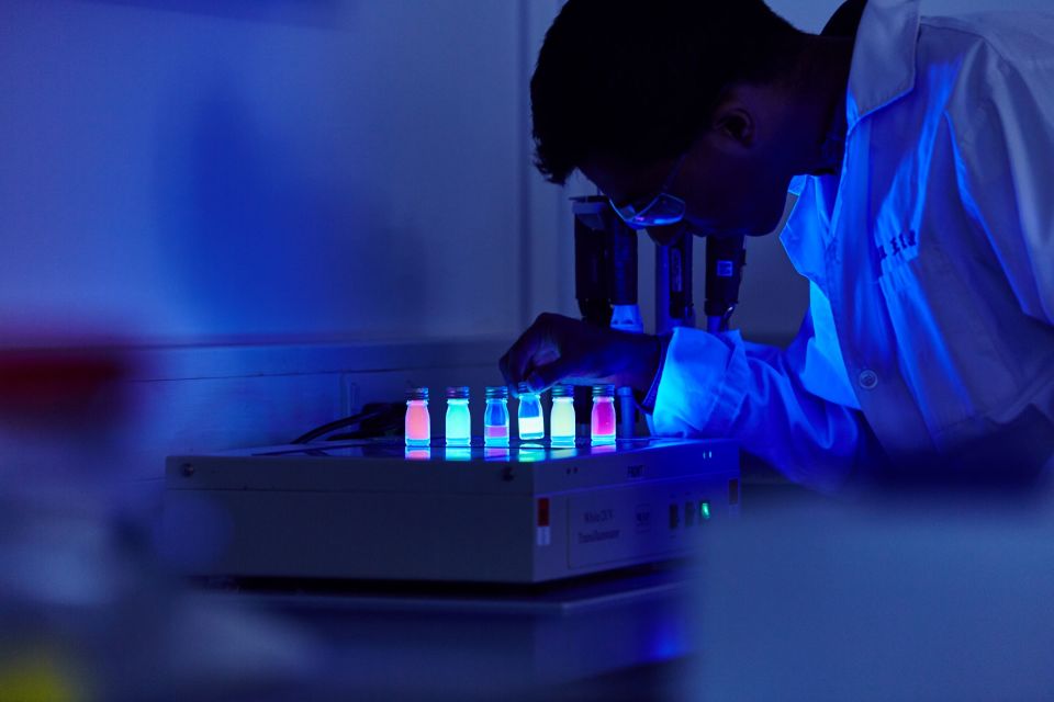 man in dark lab with test tubes glowing