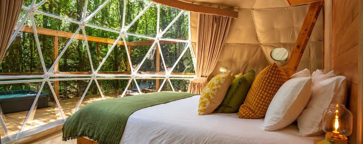 Lit confortable à l'intérieur du dome avec vue sur la foret et la terrasse
