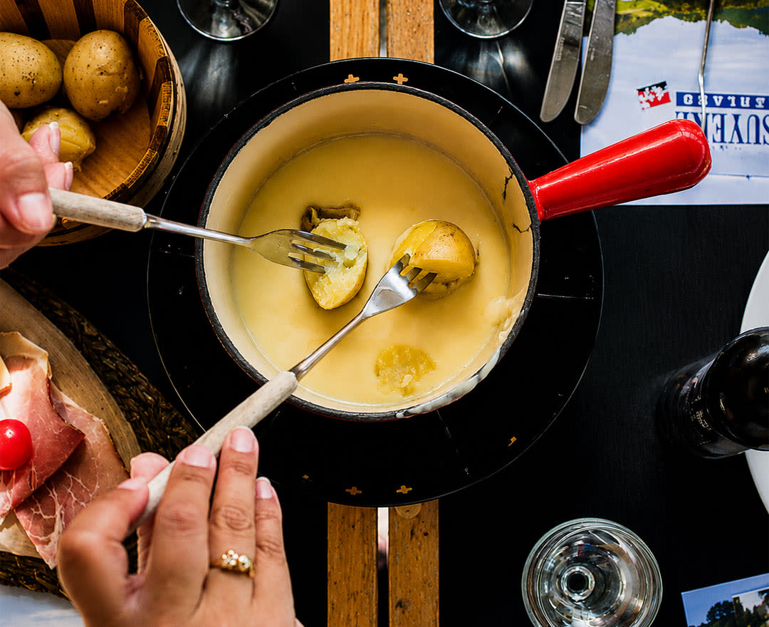 Une fondue fumante à partager, entourée de charcuteries, de saumon fumé, de sauces et d’un verre de vin, dans une ambiance chaleureuse et conviviale.