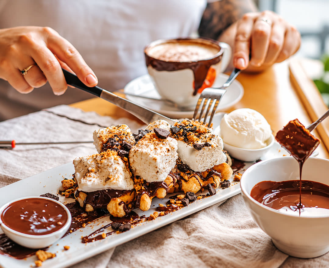 Un brownie garni de noix de pécan accompagné d’un assortiment décadent de boissons chocolatées et de milkshakes gourmands.
