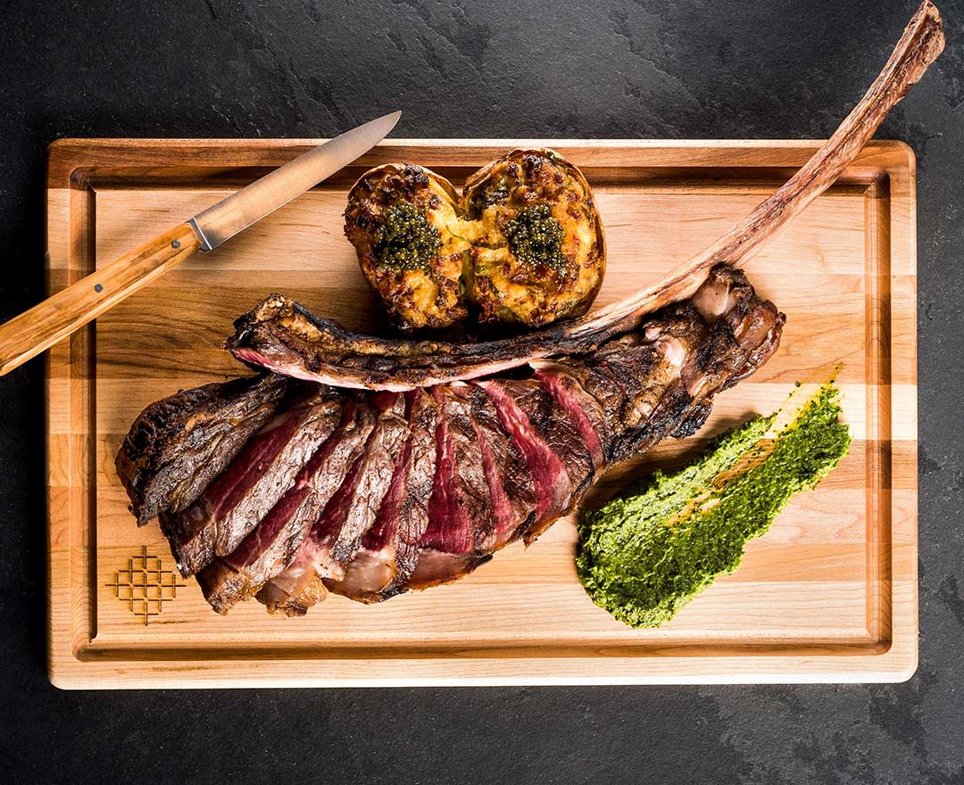 Une généreuse pièce de viande grillée et tranchée, accompagnée de légumes et d’une sauce aux herbes