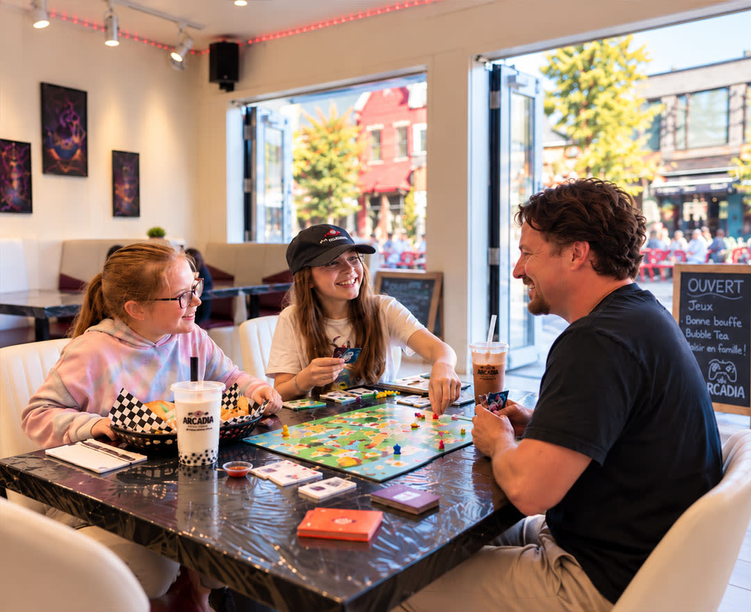 Un groupe de personnes profite d’un moment convivial autour de jeux de société dans une ambiance chaleureuse et animée.
