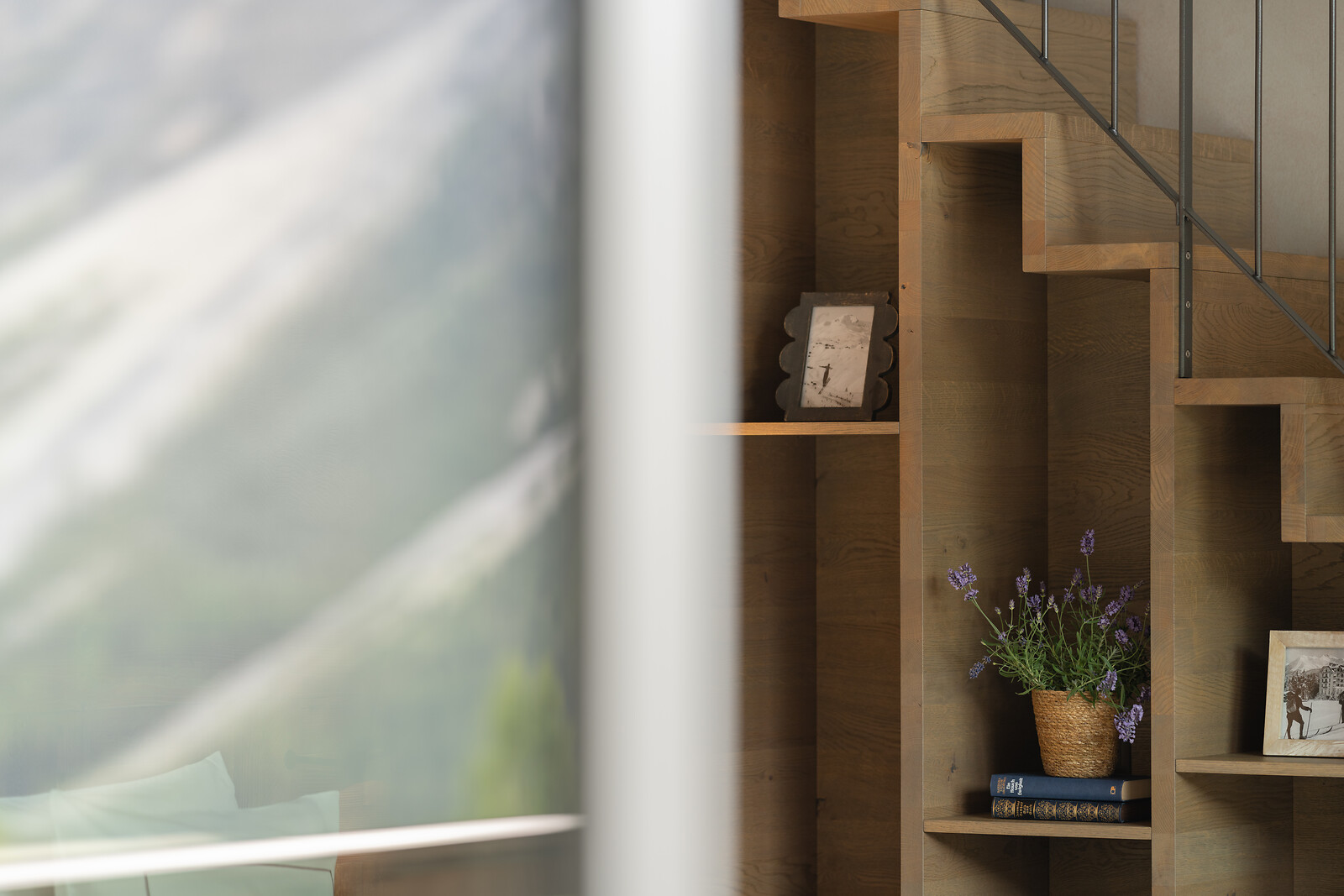 Detailansicht einer Treppe mit integrierten Regalfächern, dekoriert mit Büchern, Pflanzen und persönlichen Wohnaccessoires.