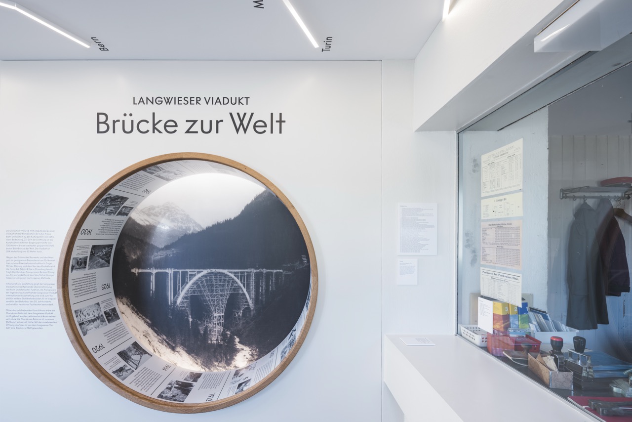 Museumsausstellung mit rundem Bild des Langwieser Viadukts und Titel "Brücke zur Welt" an weisser Wand.