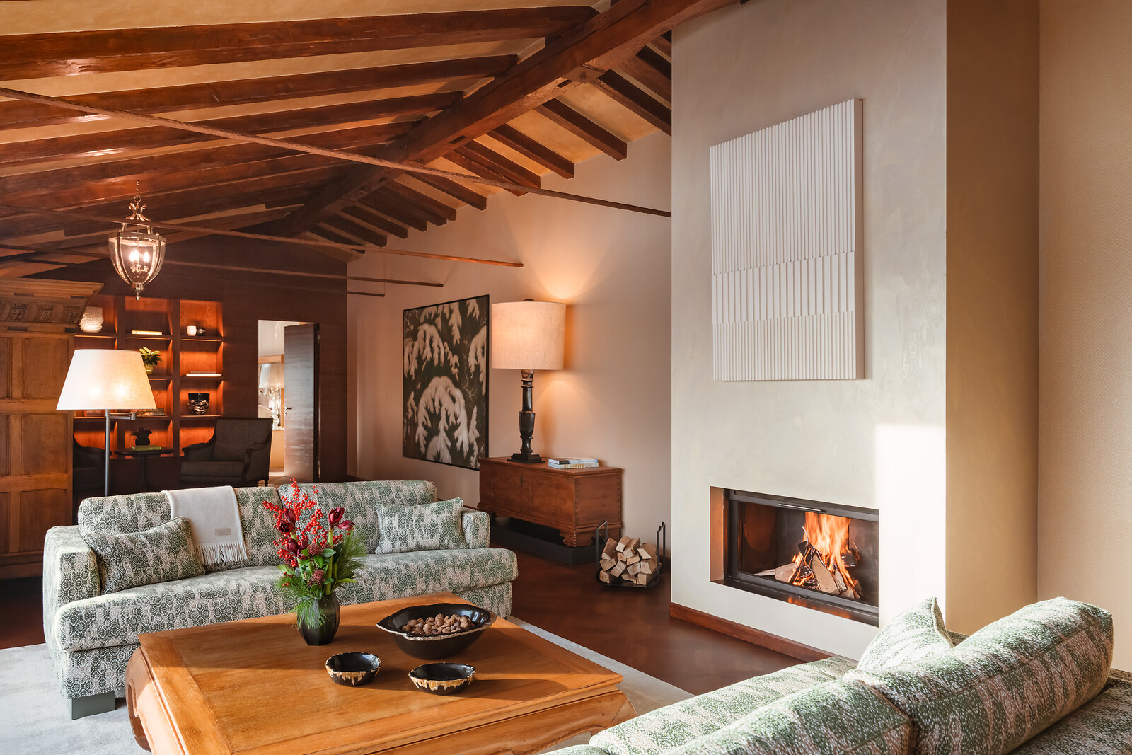 Hauptraum des Penthouses mit Kamin, komfortablen Sofas und einem Tisch mit ausgewählten Annehmlichkeiten.