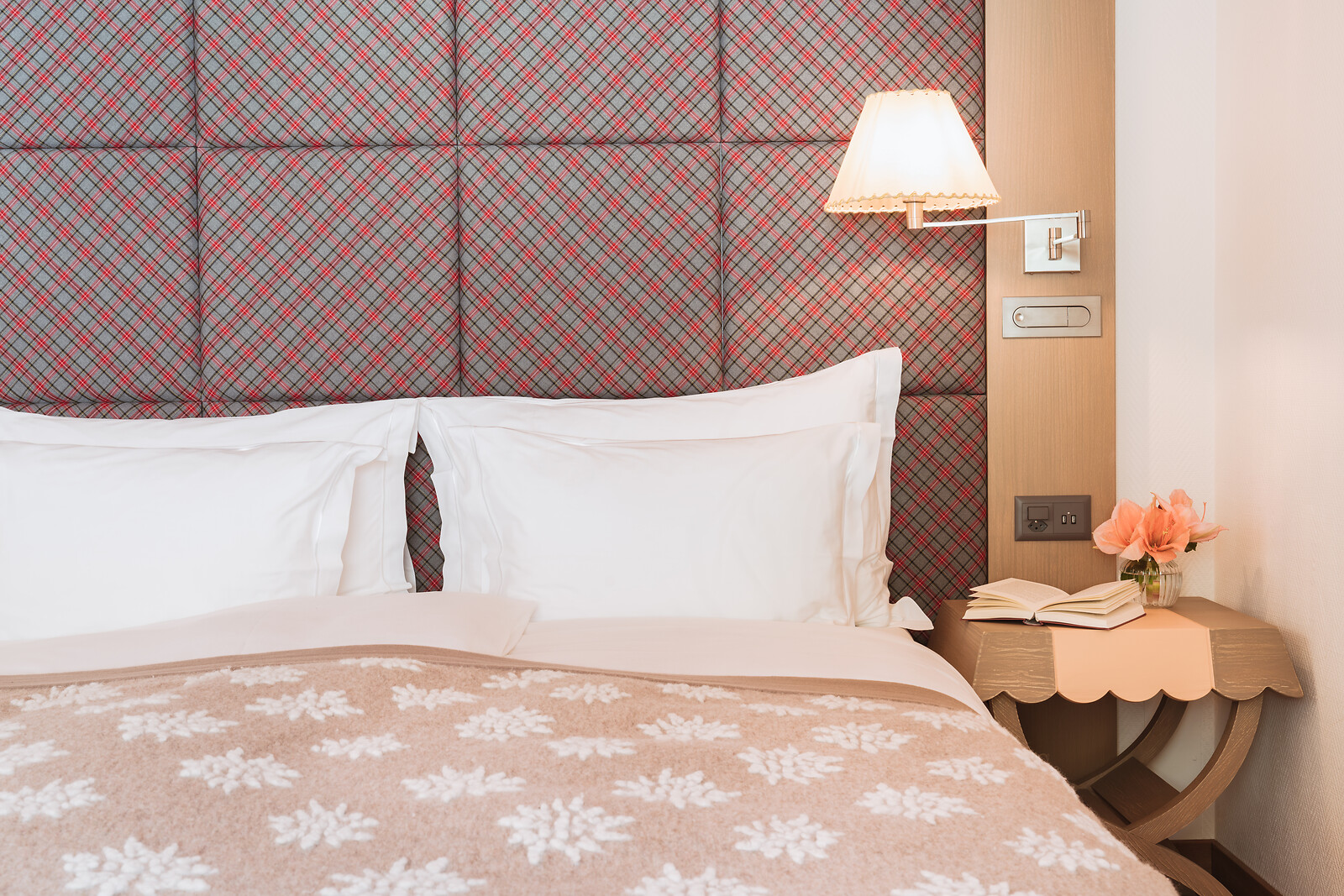 Hotelzimmer mit floralem Kopfteil, grünen Stühlen, einem Schreibtisch am Fenster und einer dekorativen Decke mit Blick auf die Berge.