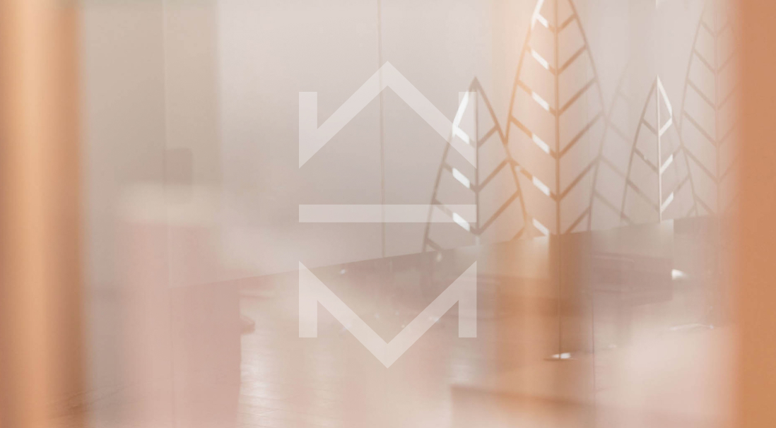 Weiße Draht-Weihnachtsbäume und Kerzen auf einer neutralen beigefarbenen Oberfläche, die ein sanftes, festliches Arrangement bilden.