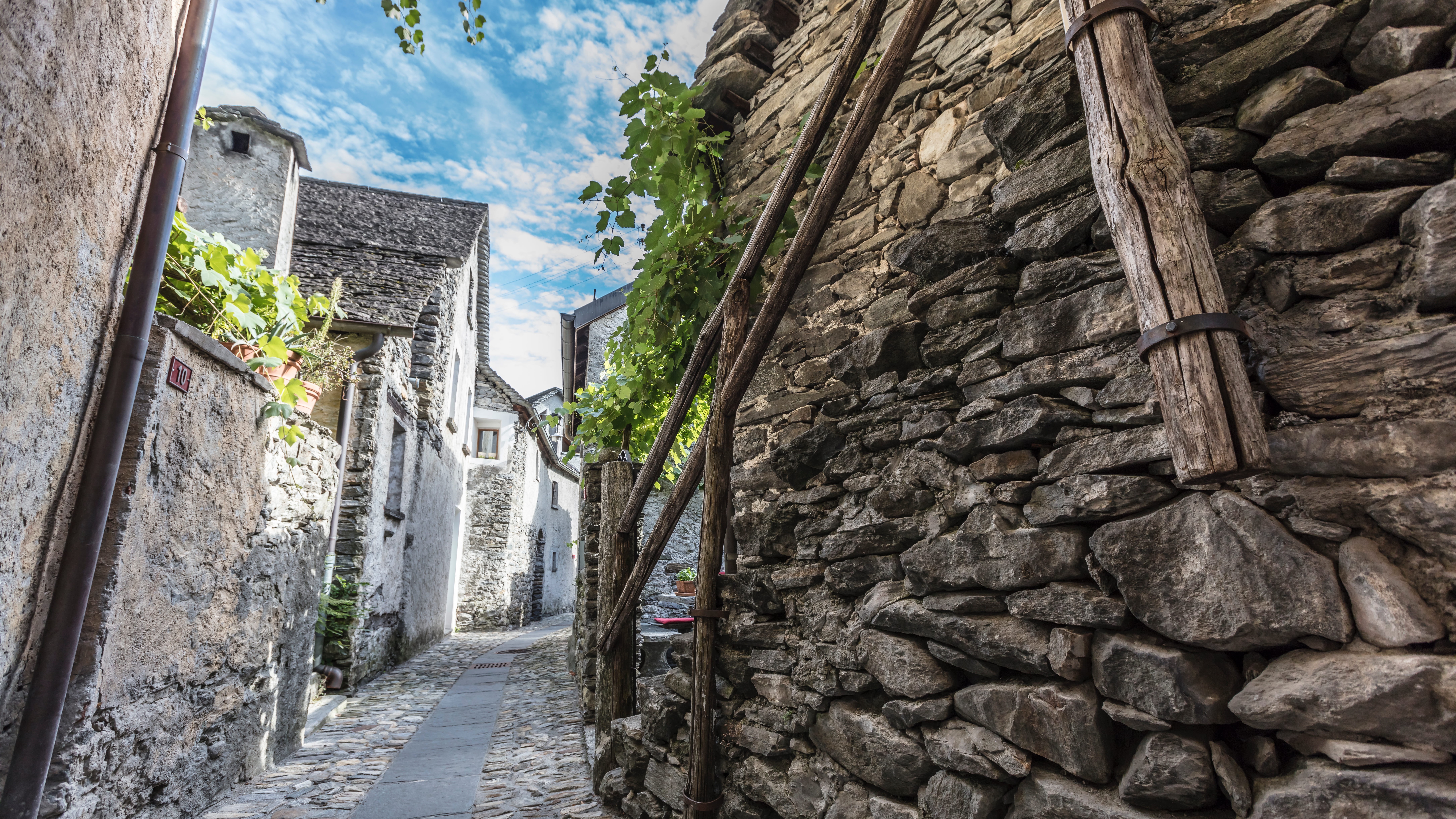 Schmale gepflasterte Gasse mit Natursteinhäusern und Holzbalken im Dorf Giumaglio im Maggiatal.