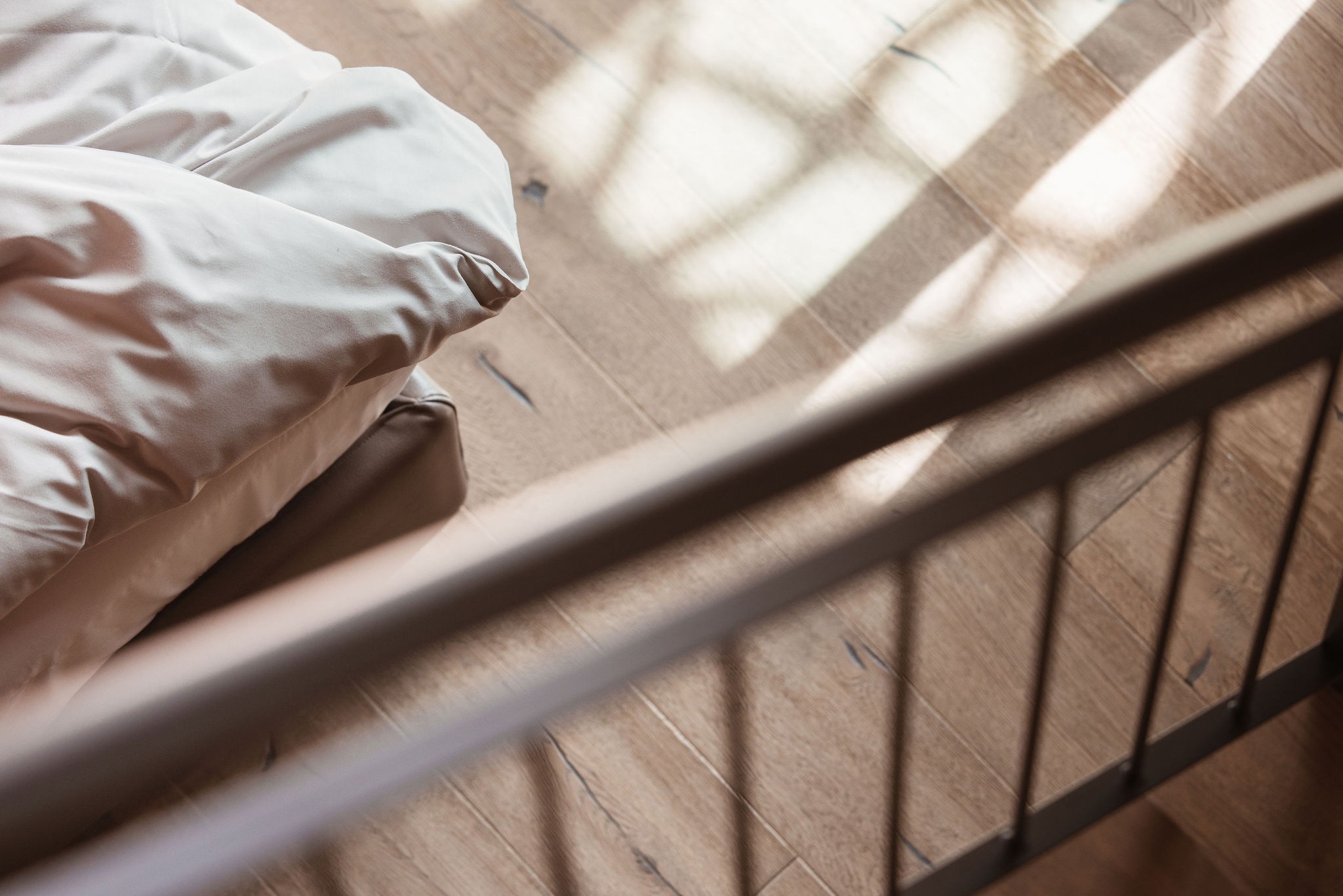 Person in white shirt standing on wooden floor with window shadow patterns creating geometric lines across the surface.