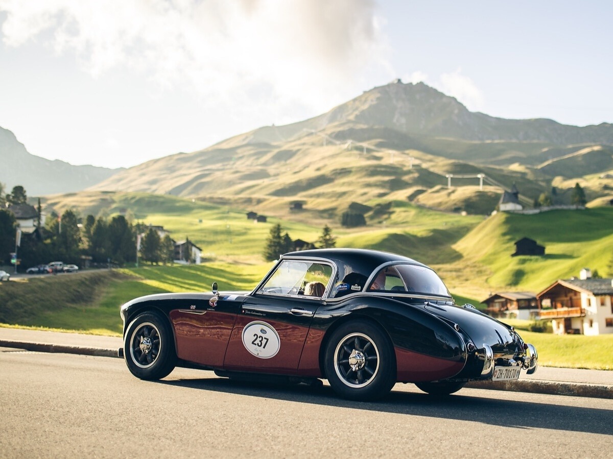 Vintage roadster at the Arosa ClassicCar event, set against green Alpine meadows and a mountainous backdrop in Arosa.
