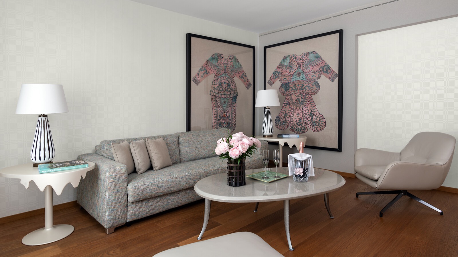 Stilvolles Wohnzimmer mit Designer-Couch, asiatischer Wandkunst in großem Format, frischen Rosen auf dem Couchtisch und Champagner mit Gläsern.