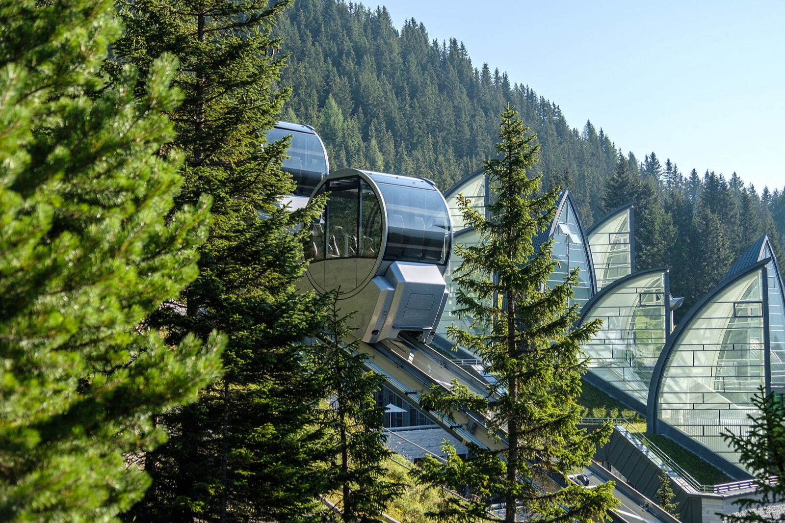 Der Tschuggen Express fährt durch einen dichten Nadelwald hinauf zum futuristisch gestalteten Tschuggen Bergoase Spa in den Bergen von Arosa.