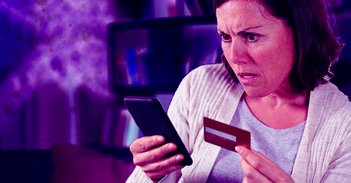 Woman looking frightened at phone holding credit card