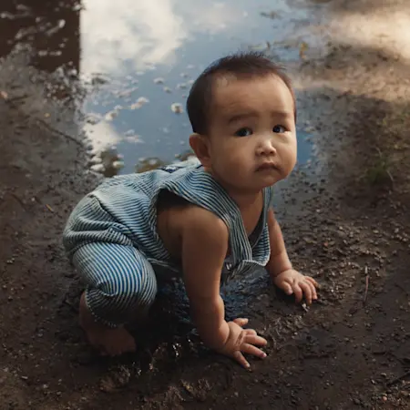 sad baby sitting in mud