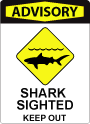 A sign with bold red text at the top that says "Advisory" with iconography depicting a shark swimming near the beach. Text at the bottom of the sign says "Shark sighted, keep out."